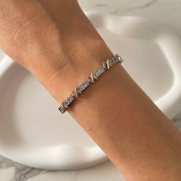 Pulseira riviera com detalhe em x dourado o banho de ródio branco