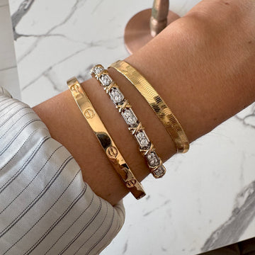 Pulseira riviera com detalhe em x dourado o banho de ródio branco